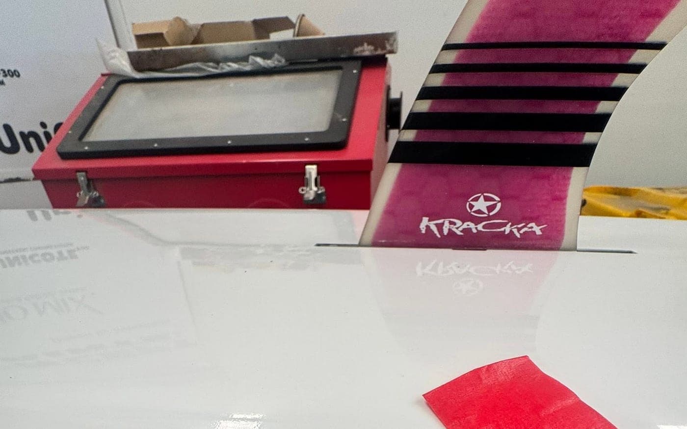 A Kracka surf ski on the bench at Warana, masked up in red tape for a colour-matched repair to its deck